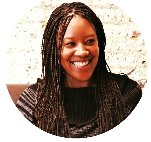 Team Sesi. Headshot of Andrea Butler, Sesi magazine's editor-in-chief/publisher. She's a Black woman wearing long box braids and a black and gray sweater. 