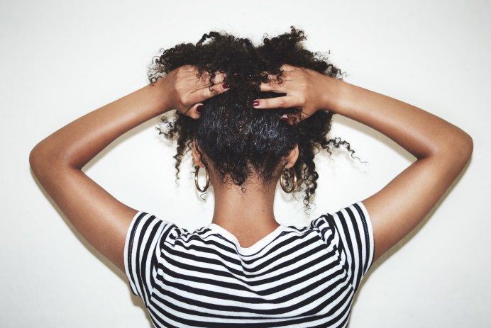 Back of Black girl holding up her curly hair