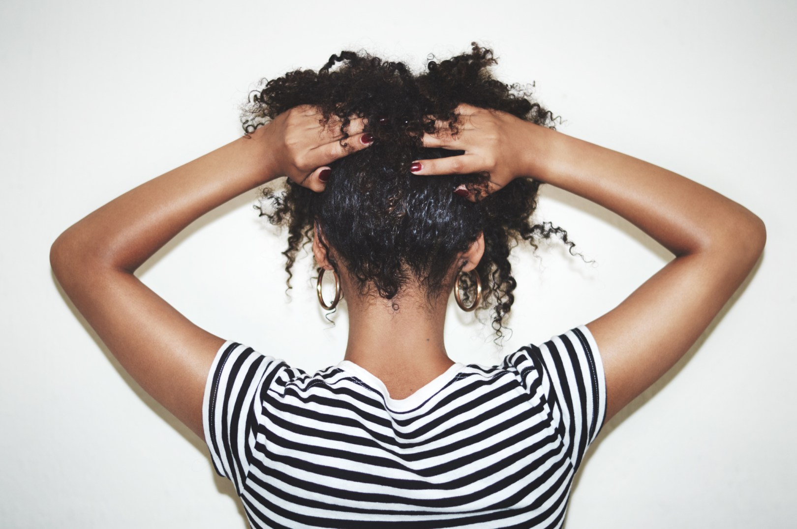 Back of Black girl holding up her curly hair