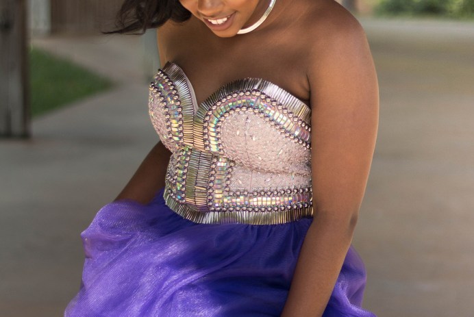 black girl wearing prom dress with beaded bodice and purple tulle skirt