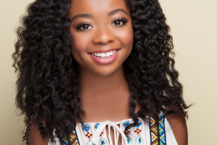 Skai Jackson wearing a white, open-shouldered shirt with mosaic beading details