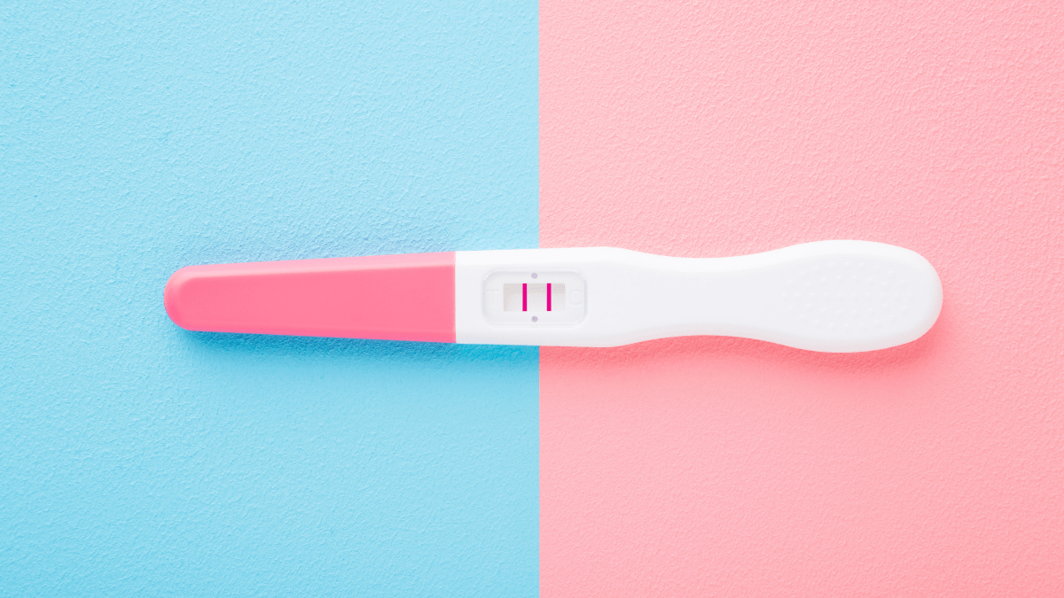 positive pregnancy test on blue and pink background