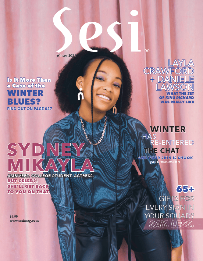 Sydney Mikayla covers Sesi magazine's winter 2021 issue. She's wearing her natural hair in a ponytail poof with two small braids on each side in the front. Her shirt is a marbled dark blue with black leather pants. The cover background is pink.