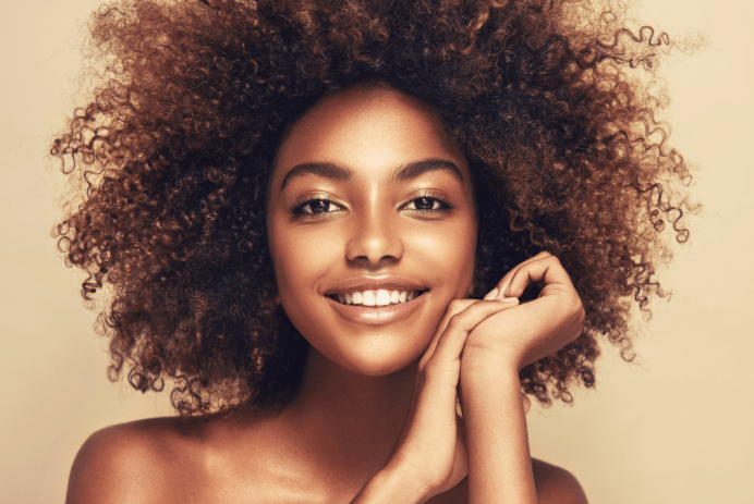 Black teen girl with clear skin and a golden glow; hair in a big, curly afro