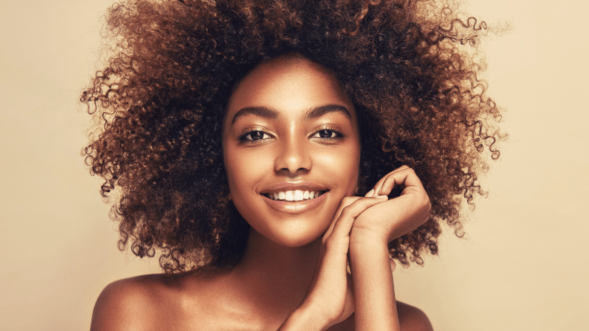 Black teen girl with clear skin and a golden glow; hair in a big, curly afro
