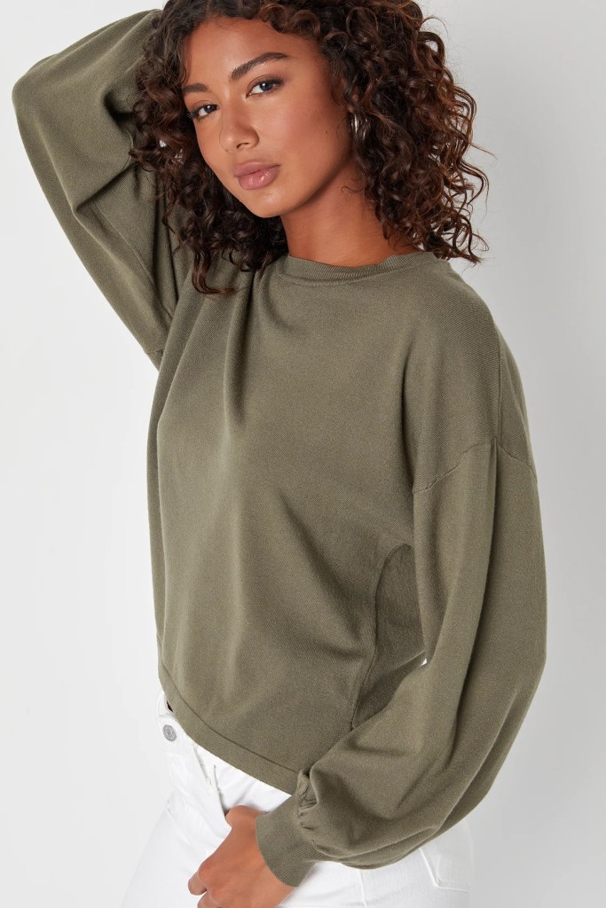Brown-skinned Black girl with curly hair wearing an olive green, cozy fall sweater