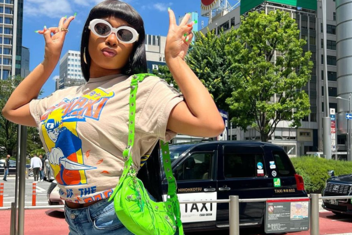 Megan Thee Stallion posing with two hand peace signs in Japan