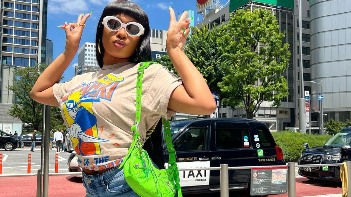 Megan Thee Stallion posing with two hand peace signs in Japan